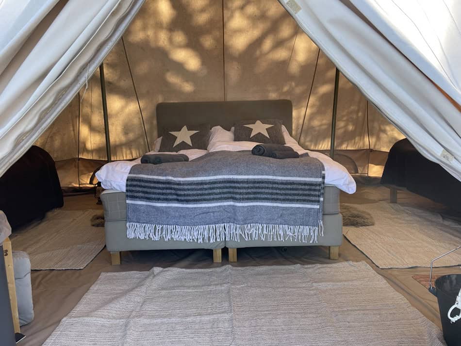 Bild på öppningen i ett glamping tält. Man ser in mot öppna ytan med en bekväm riktigt säng.